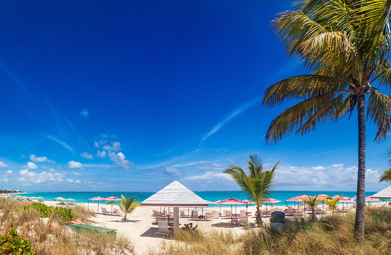 A long sweep of the white sands and turquoise waters of Grace Bay beach, in Providenciales, on a sunny spring morning, image by Jo Ann Snover